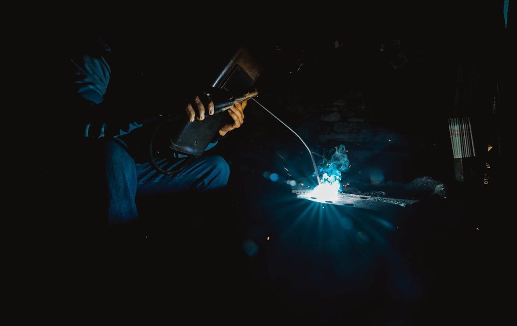 Close-up of a welder working with sparks at night, showcasing industrial skill and precision.